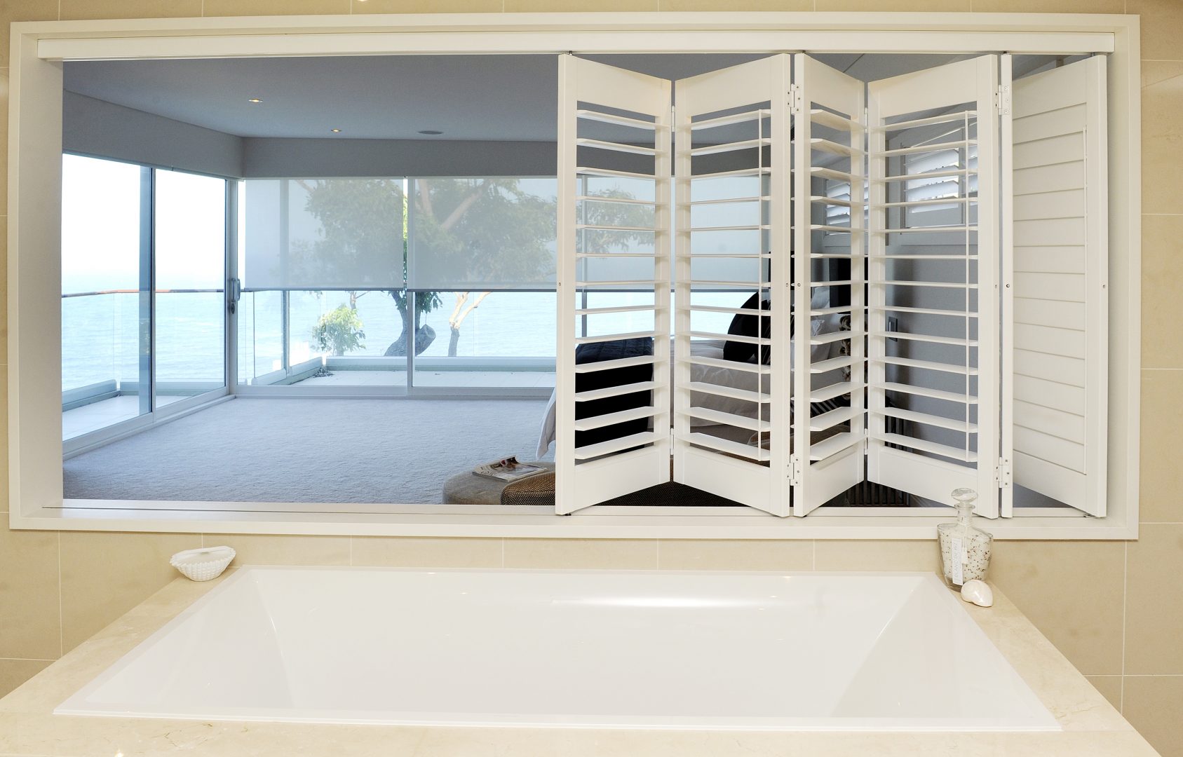 Multi-fold white plantation shutters in a modern ensuite.
